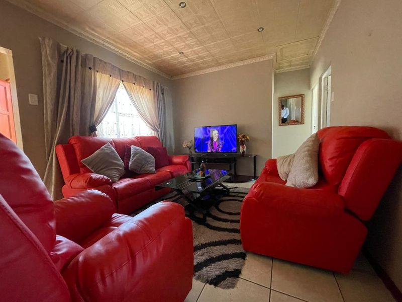 A living room featuring tiled flooring and a textured ceiling, offering a functional space that could benefit from modern updates to finishes.
