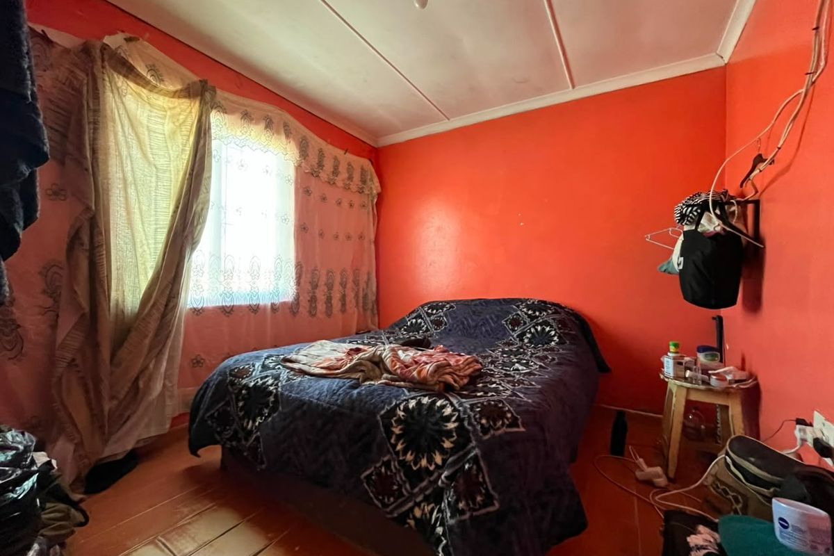 A bedroom featuring tiled flooring and ceiling panels, currently requiring cosmetic updates to the wall finishes and electrical fixtures.