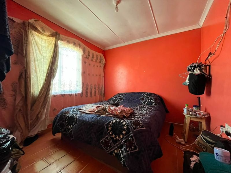 A bedroom featuring tiled flooring and ceiling panels, currently requiring cosmetic updates to the wall finishes and electrical fixtures.