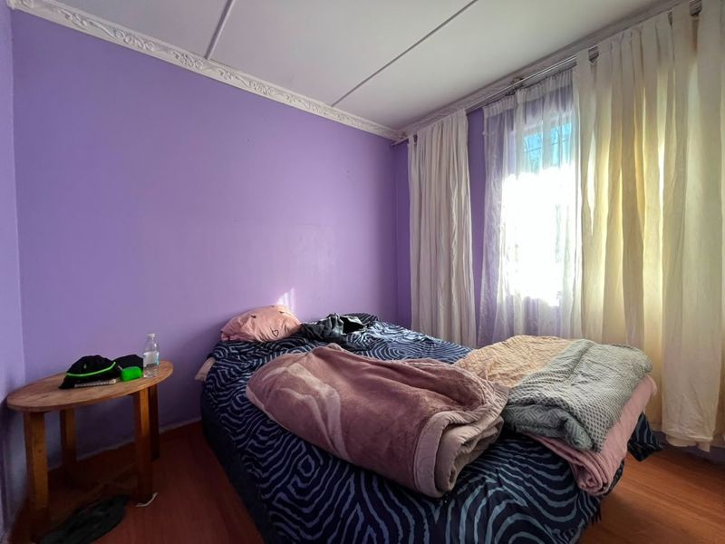 A bedroom featuring laminate flooring and decorative ceiling cornicing, providing a functional space ready for personalization.