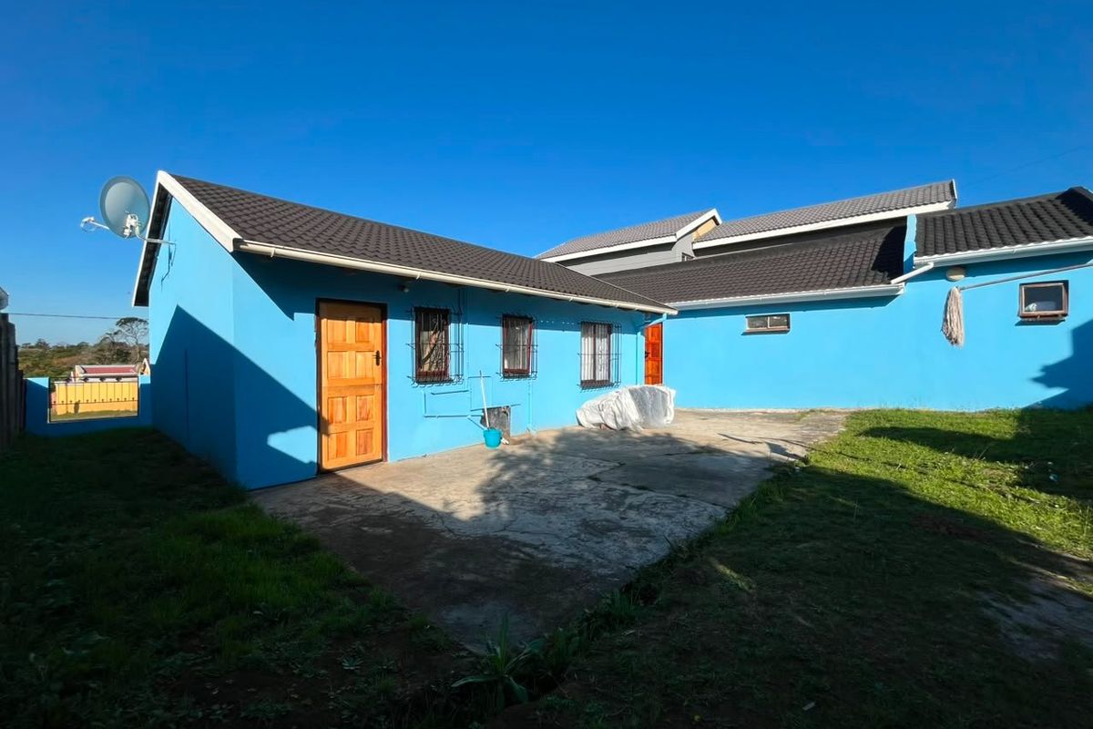 Rear view of the property featuring a concrete patio area, tiled roofing, and security bars on the windows.