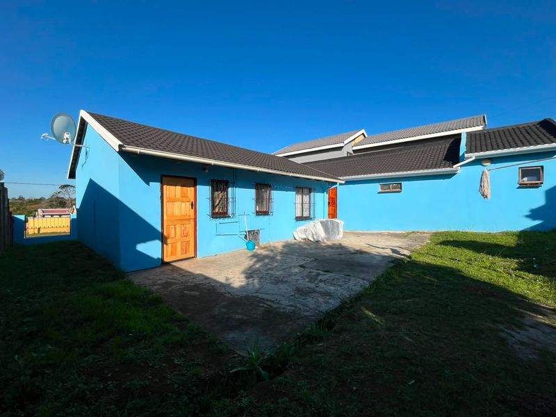 Rear view of the property featuring a concrete patio area, tiled roofing, and security bars on the windows.