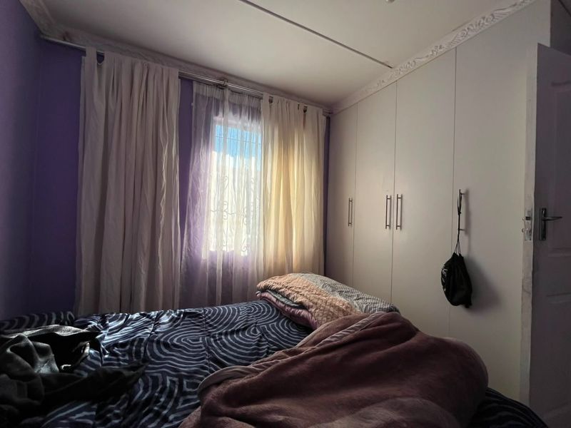 A bedroom featuring built-in cupboards and decorative ceiling cornicing, providing functional storage space.