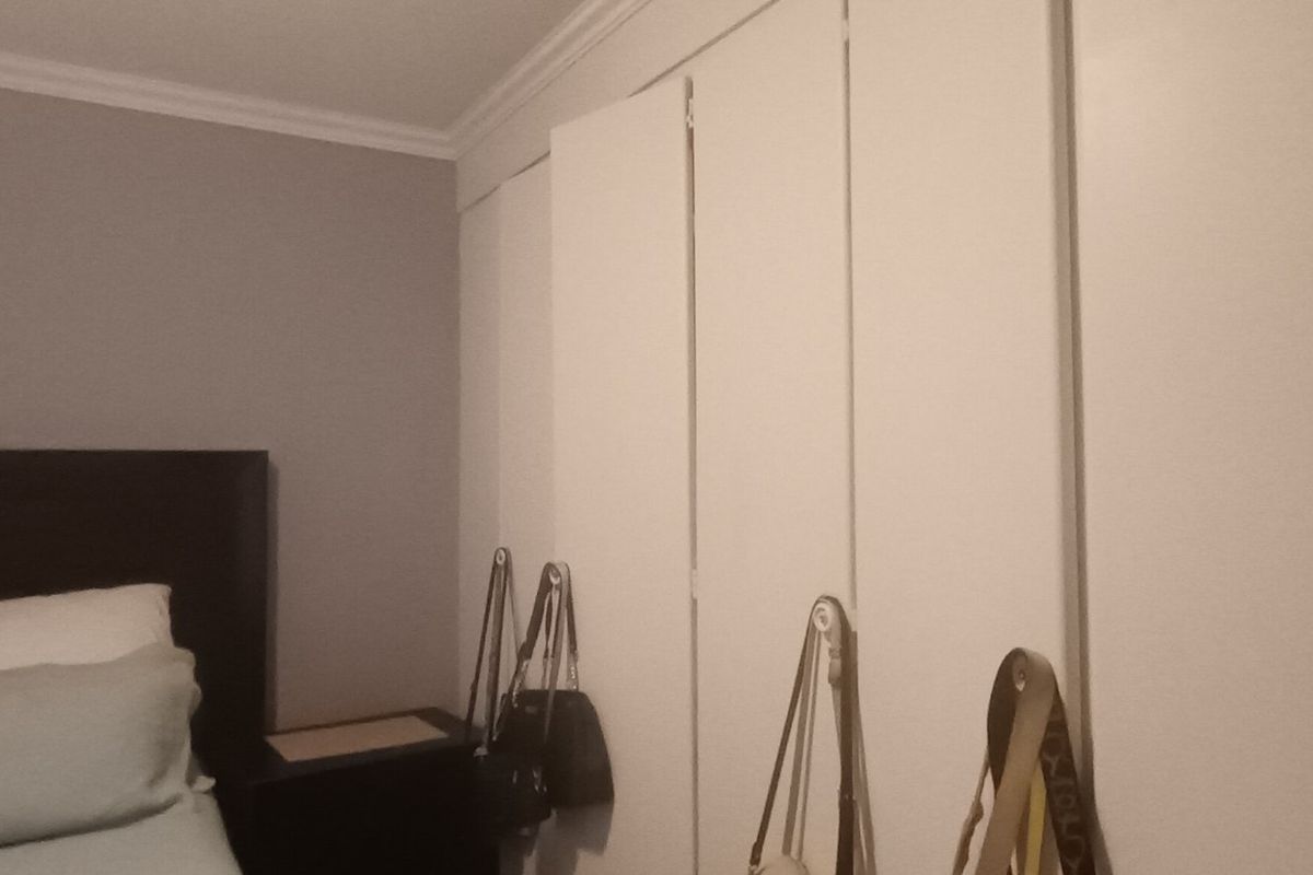 A bedroom featuring a wall of white built-in wardrobes and decorative crown molding.