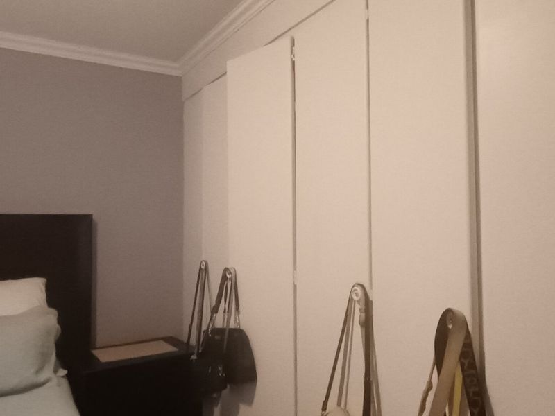 A bedroom featuring a wall of white built-in wardrobes and decorative crown molding.