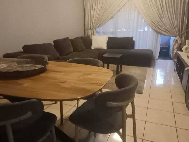 Open-plan living and dining area featuring tiled flooring and access to a balcony through a sliding glass door.