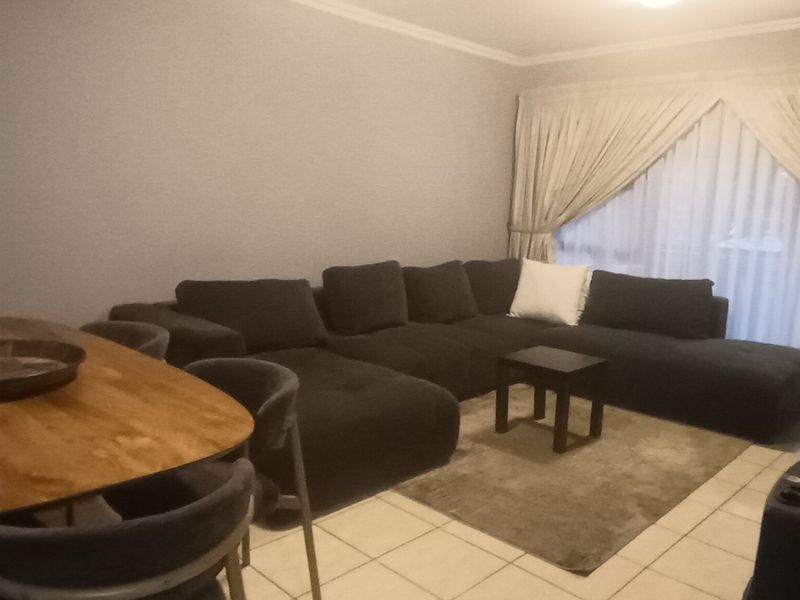 Open plan living and dining area featuring tiled flooring and access to a balcony through a large sliding glass door.