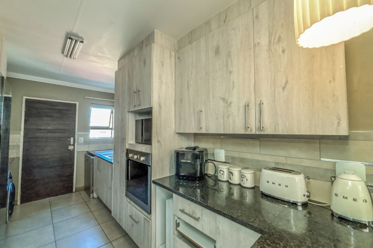 A functional kitchen featuring light wood-look cabinetry, granite countertops, built-in oven and microwave, and tiled flooring.