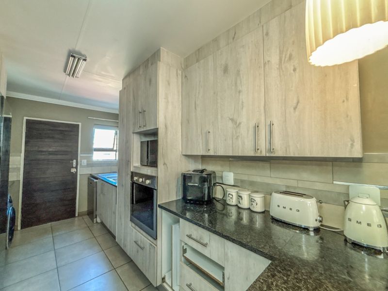 A functional kitchen featuring light wood-look cabinetry, granite countertops, built-in oven and microwave, and tiled flooring.