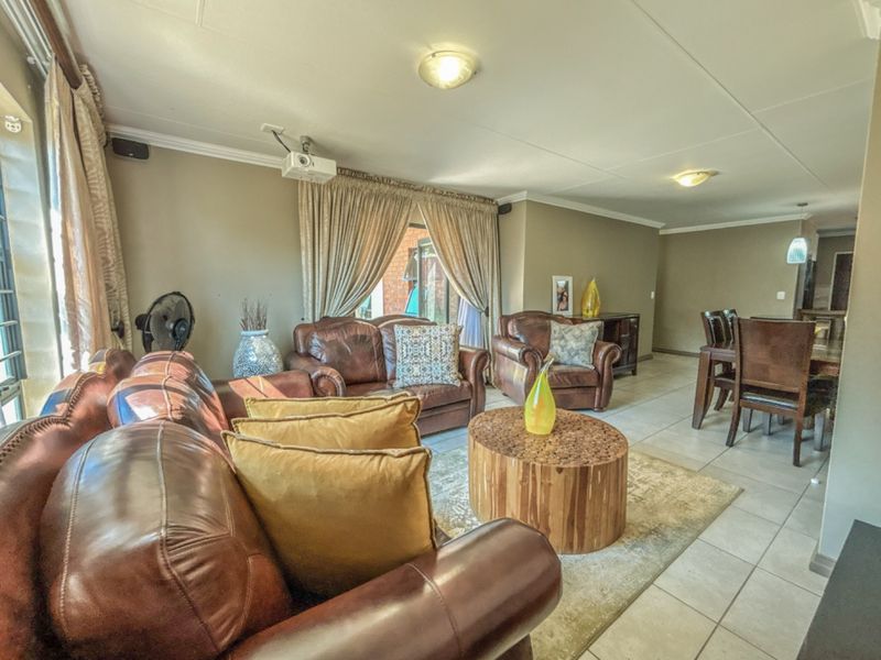Open plan living and dining area featuring tiled flooring, coved ceilings, and a ceiling-mounted projector, providing a functional space for relaxation and entertainment.