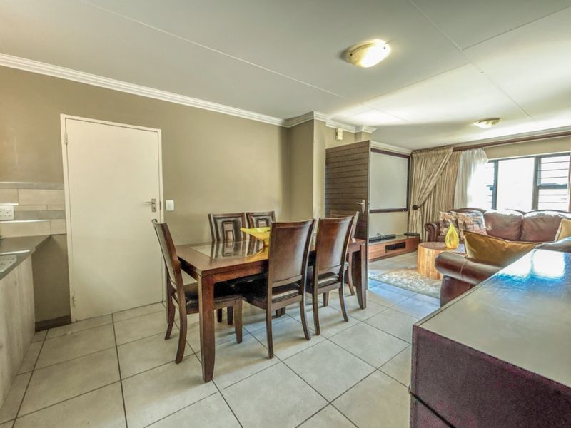 Open-plan living and dining area featuring tiled flooring, cove cornicing, and neutral wall tones, providing a functional space for daily living.