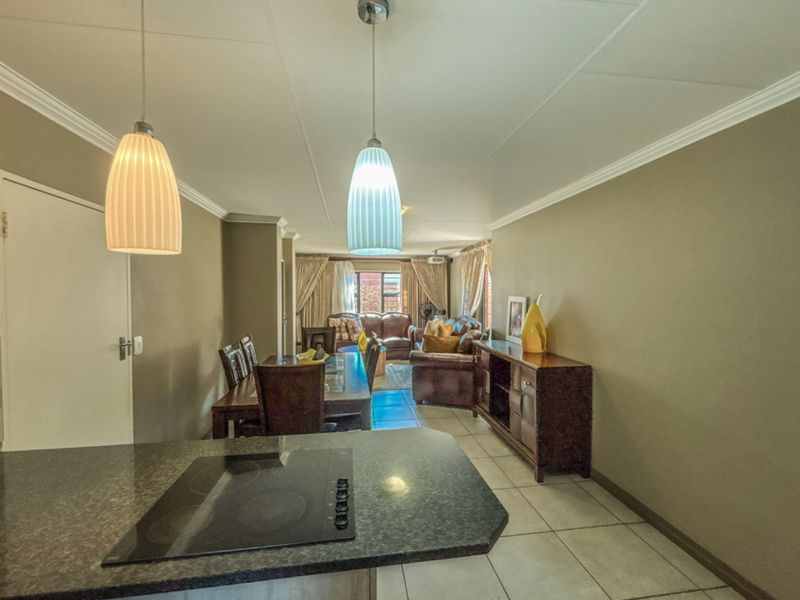 Open-plan living and dining area featuring tiled flooring, coved ceilings, and a kitchen peninsula with a built-in hob.