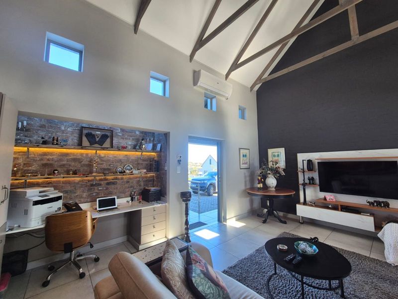 Spacious living area featuring a vaulted ceiling with exposed timber trusses, an integrated brick-walled study nook, and modern tiled flooring.
