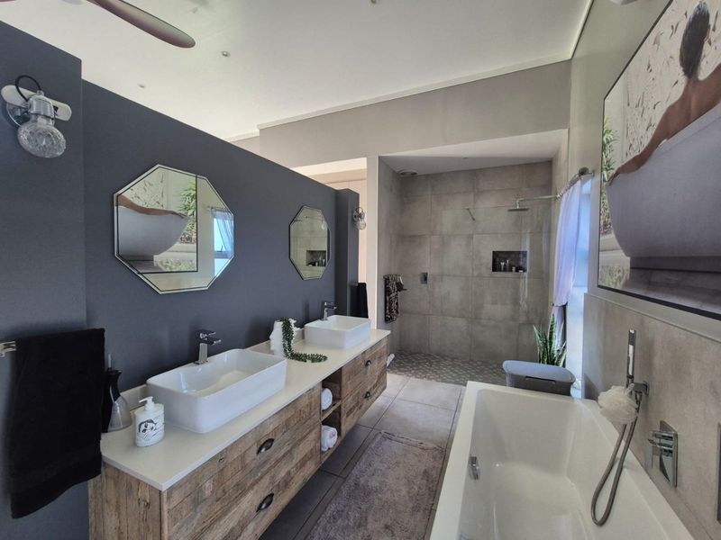 Modern bathroom featuring a double vanity with vessel sinks, a spacious walk-in shower with tiled walls, and a separate freestanding bathtub.