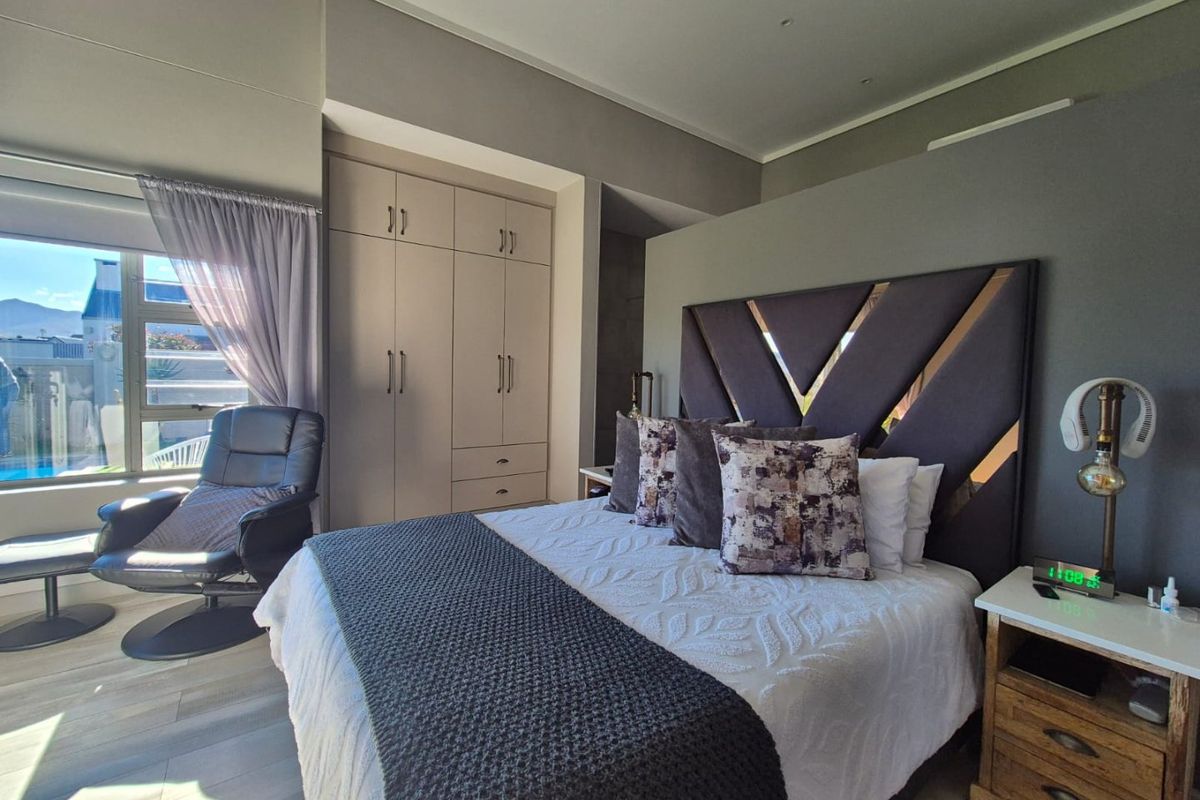 A well-maintained bedroom featuring built-in cupboards, recessed ceiling lighting, and modern laminate flooring with natural light from the window.