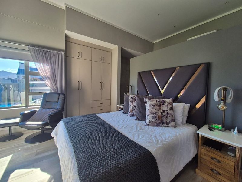 A well-maintained bedroom featuring built-in cupboards, recessed ceiling lighting, and modern laminate flooring with natural light from the window.