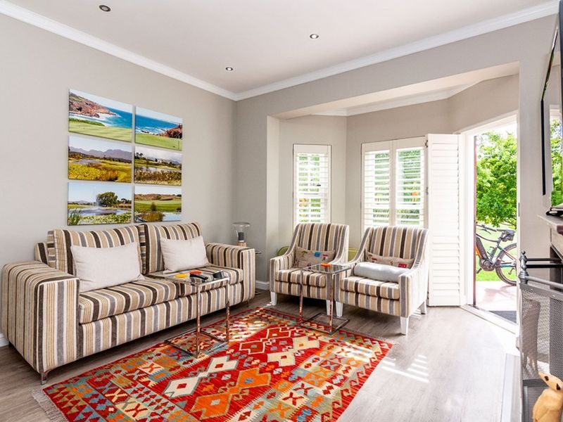 A bright living room featuring laminate flooring, recessed downlights, crown molding, and plantation shutters, with direct access to the outdoor area.