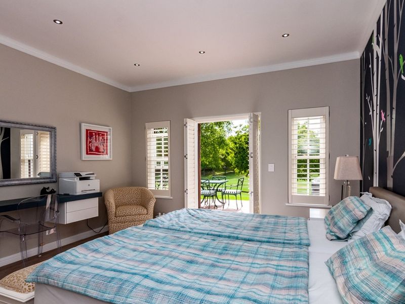Spacious bedroom featuring recessed downlights, plantation shutters, and direct access to the garden through French doors, complemented by a built-in desk area.