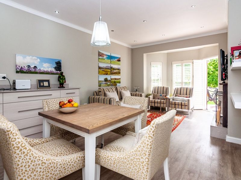 Bright open-plan living and dining area featuring laminate flooring, recessed lighting, built-in cabinetry, and direct access to the garden through french doors.