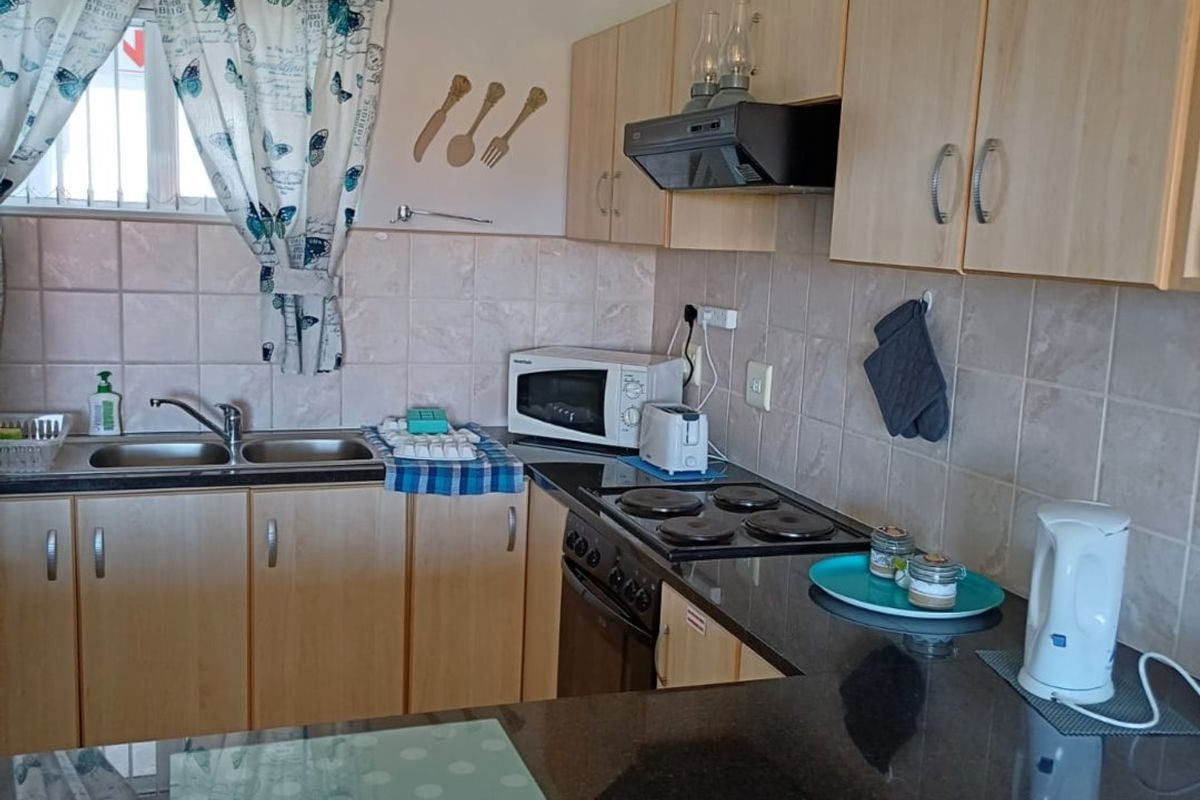 A functional kitchen featuring laminate cabinetry, granite countertops, a double bowl sink, and built-in cooking appliances with ceramic tile splashbacks.