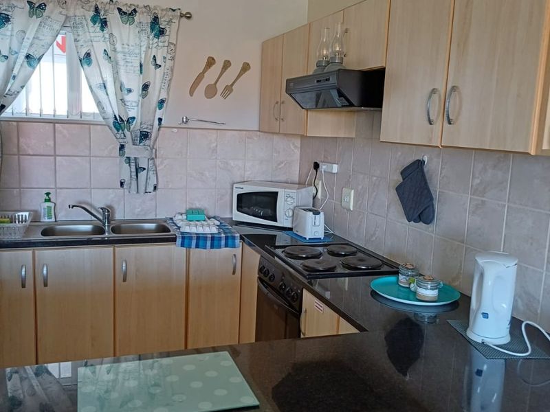 A functional kitchen featuring laminate cabinetry, granite countertops, a double bowl sink, and built-in cooking appliances with ceramic tile splashbacks.