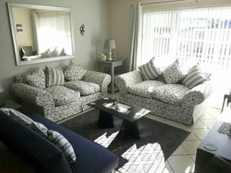 A comfortable living room featuring tiled flooring and large sliding glass doors with vertical blinds, providing natural light and access to the exterior.
