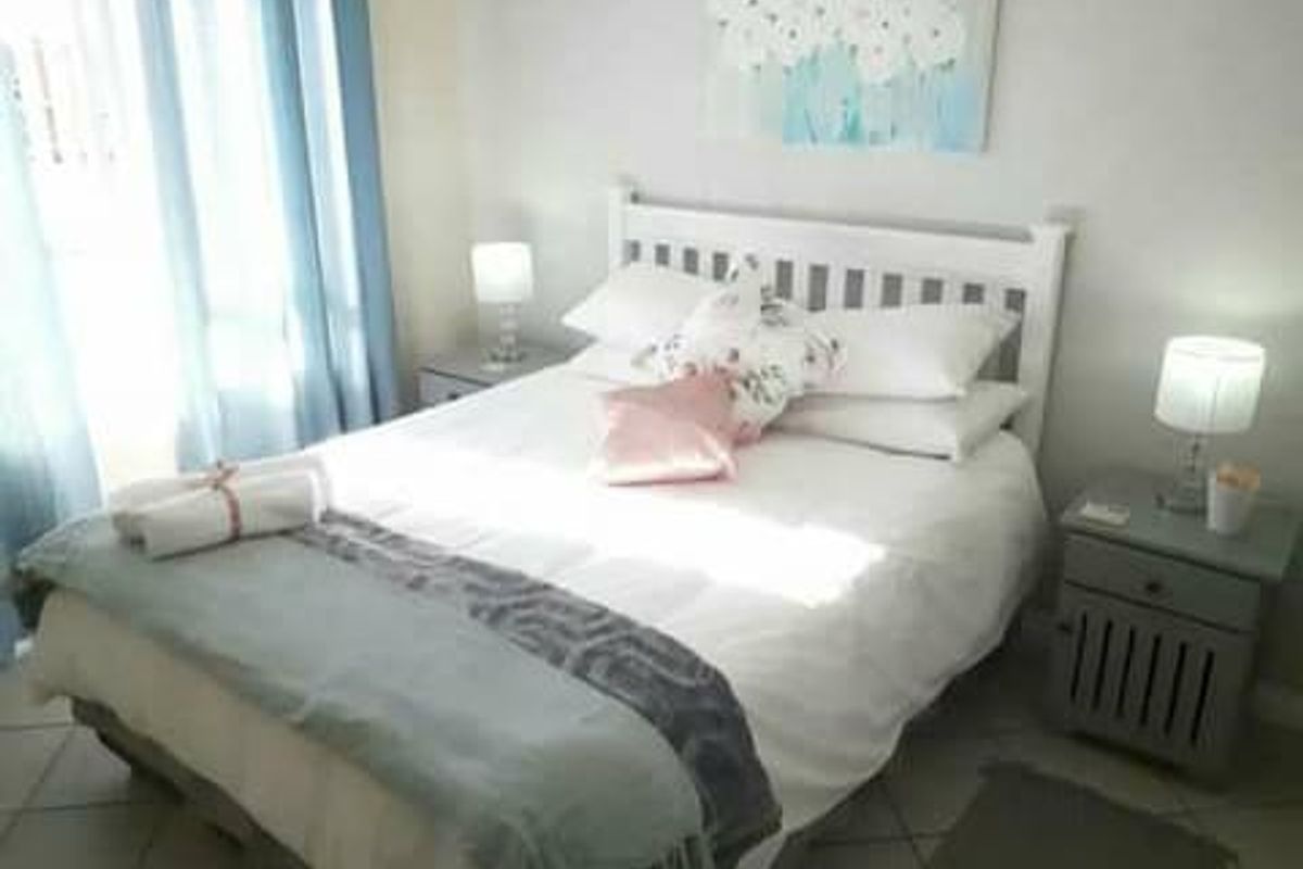 A cozy bedroom featuring tiled flooring and natural light from the window, providing a comfortable and functional sleeping space.