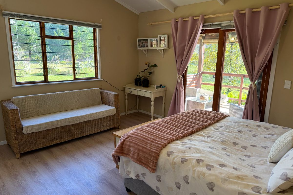 A bright bedroom featuring laminate flooring, exposed beam ceilings, and direct access to an outdoor patio through sliding glass doors.