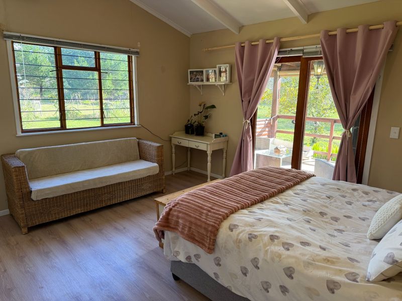 A bright bedroom featuring laminate flooring, exposed beam ceilings, and direct access to an outdoor patio through sliding glass doors.