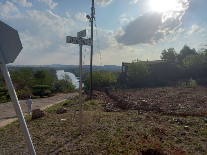 Street view of the vacant residential land corner, featuring local signage, utility infrastructure, and a view overlooking the nearby river landscape.