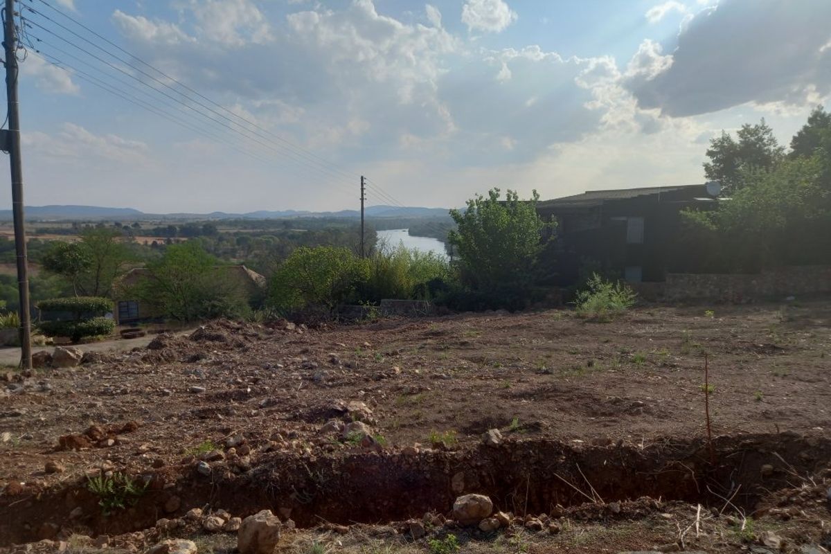 A scenic view overlooking a river and surrounding landscape from a vacant residential plot.