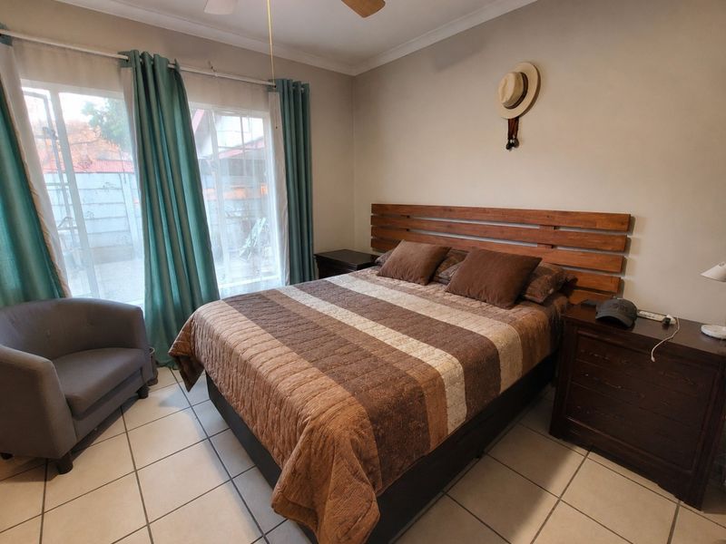 A bedroom featuring tiled flooring, a ceiling fan, and a sliding glass door providing natural light and access to the exterior.