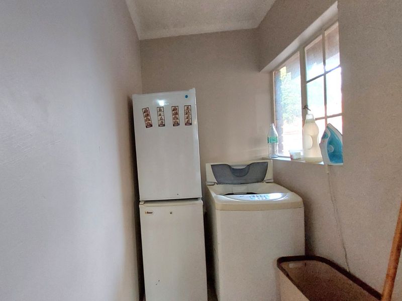 A functional laundry area featuring a window and space for appliances.