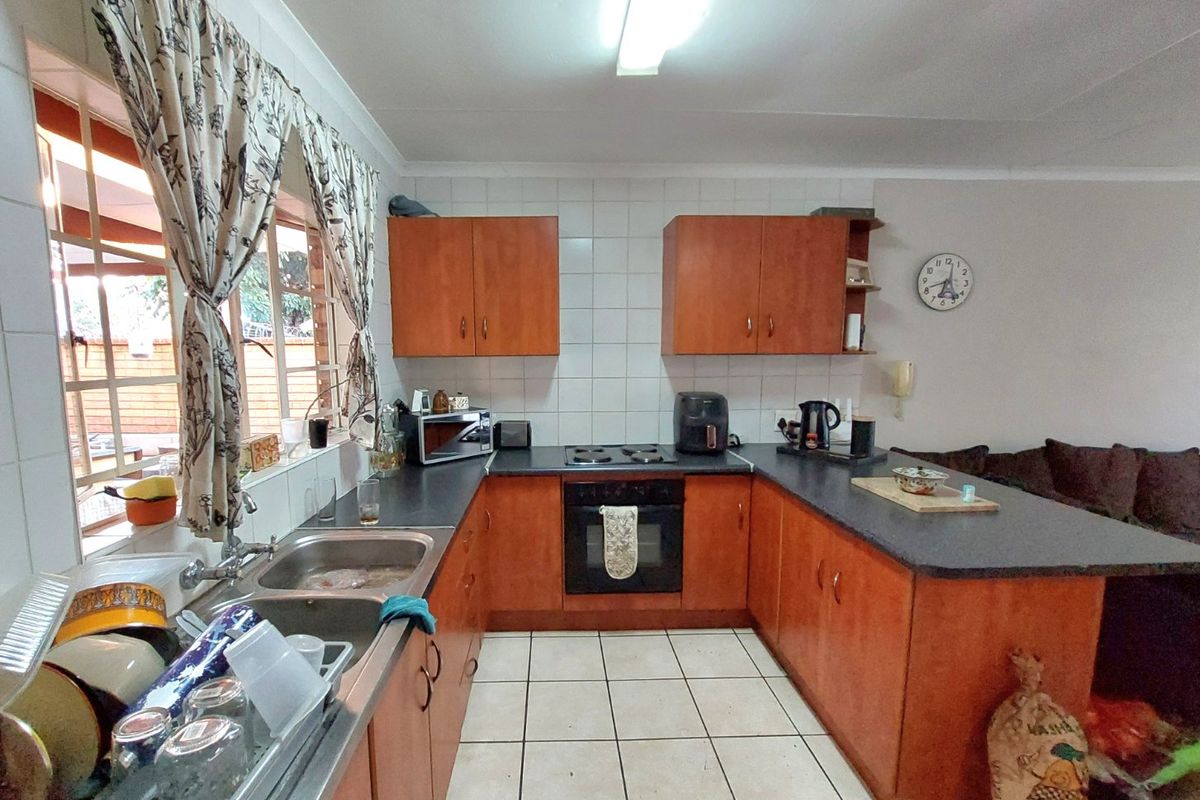 A functional kitchen featuring wooden cabinetry, laminate countertops, a built-in oven with hob, and tiled flooring, offering a practical layout for daily use.