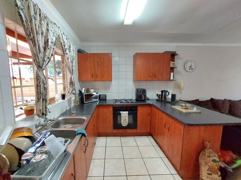 A functional kitchen featuring wooden cabinetry, laminate countertops, a built-in oven with hob, and tiled flooring, offering a practical layout for daily use.