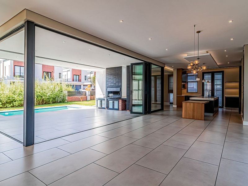 Spacious open-plan living area featuring large format floor tiles, recessed lighting, and seamless indoor-outdoor flow through bi-fold doors to the pool area.