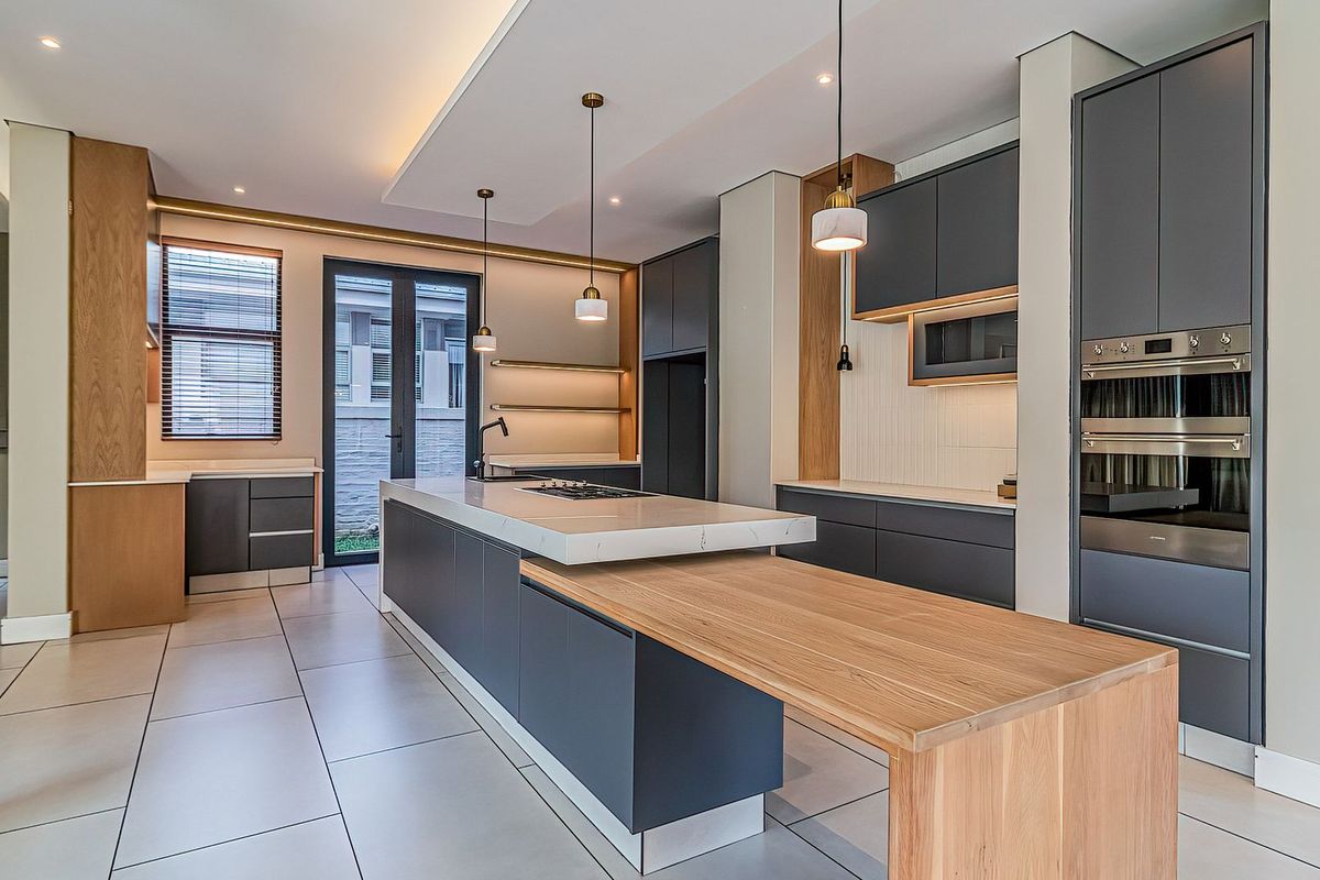 Modern, high-end kitchen featuring a large island with integrated breakfast bar, premium cabinetry, built-in appliances, and sleek stone countertops.