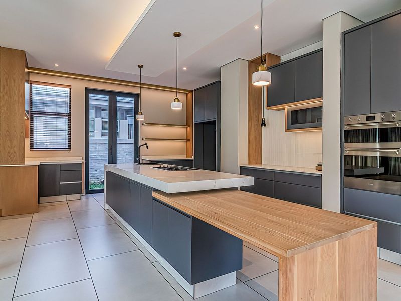 Modern, high-end kitchen featuring a large island with integrated breakfast bar, premium cabinetry, built-in appliances, and sleek stone countertops.