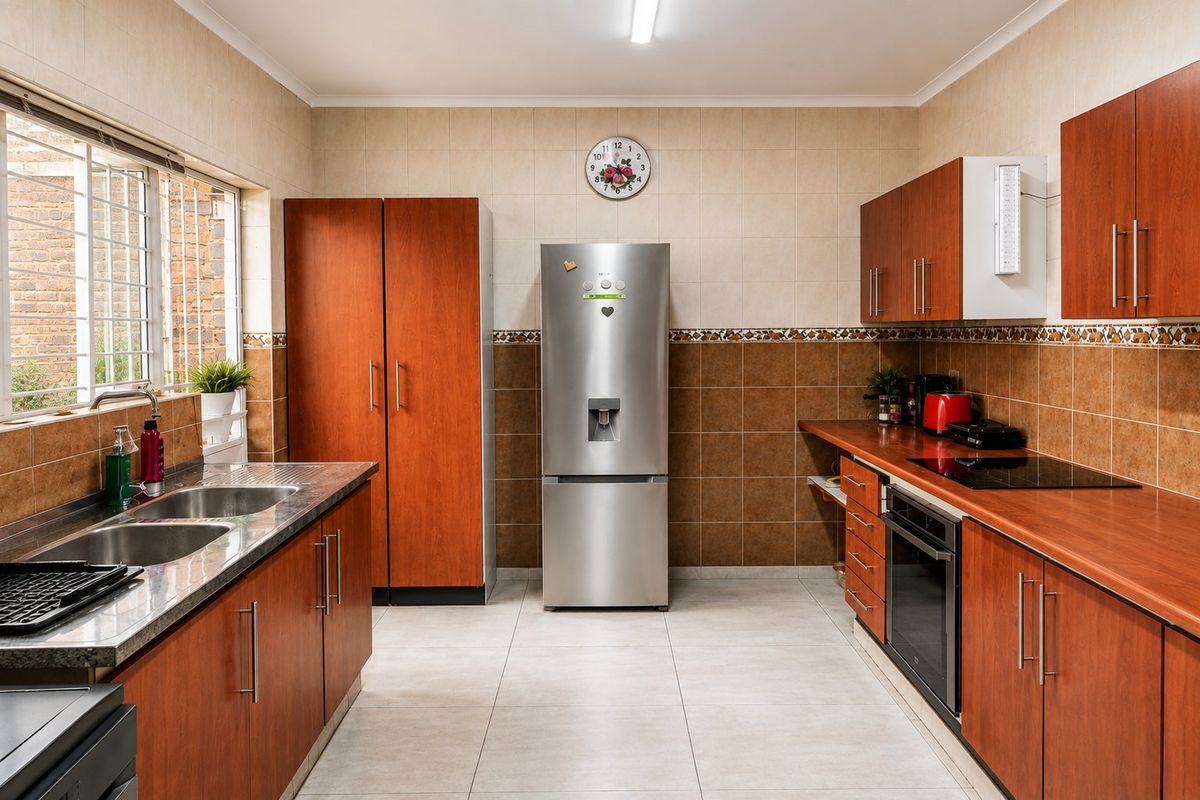 Functional kitchen featuring wood-finish cabinetry, laminate countertops, built-in oven, electric cooktop, and a double bowl stainless steel sink with tiled backsplash.