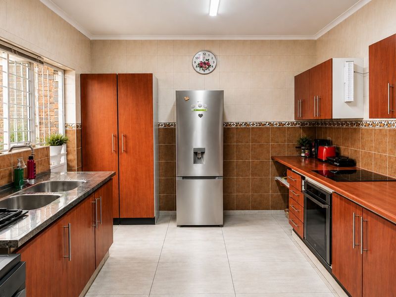 Functional kitchen featuring wood-finish cabinetry, laminate countertops, built-in oven, electric cooktop, and a double bowl stainless steel sink with tiled backsplash.