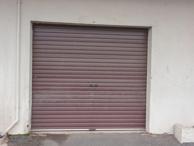 A standard garage unit featuring a brown roller shutter door and exterior wall finish.