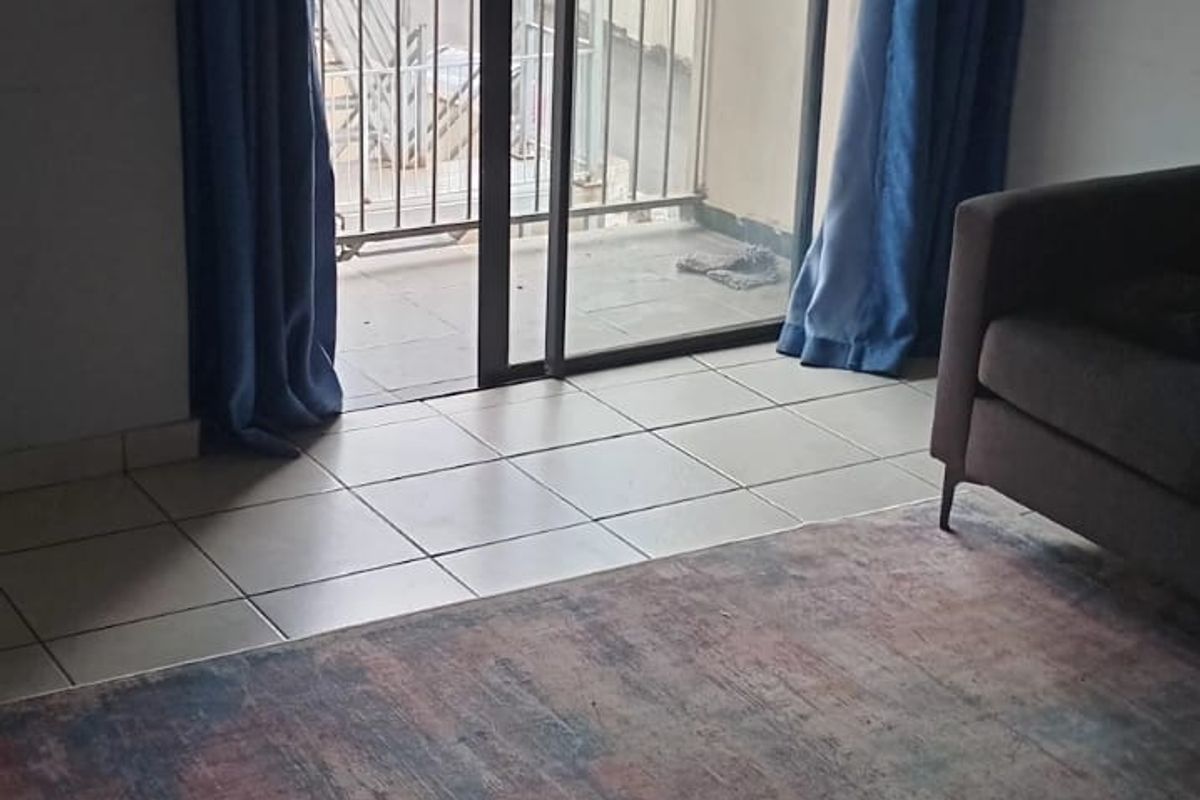 Living room area featuring tiled flooring and a sliding glass door providing direct access to an outdoor balcony.