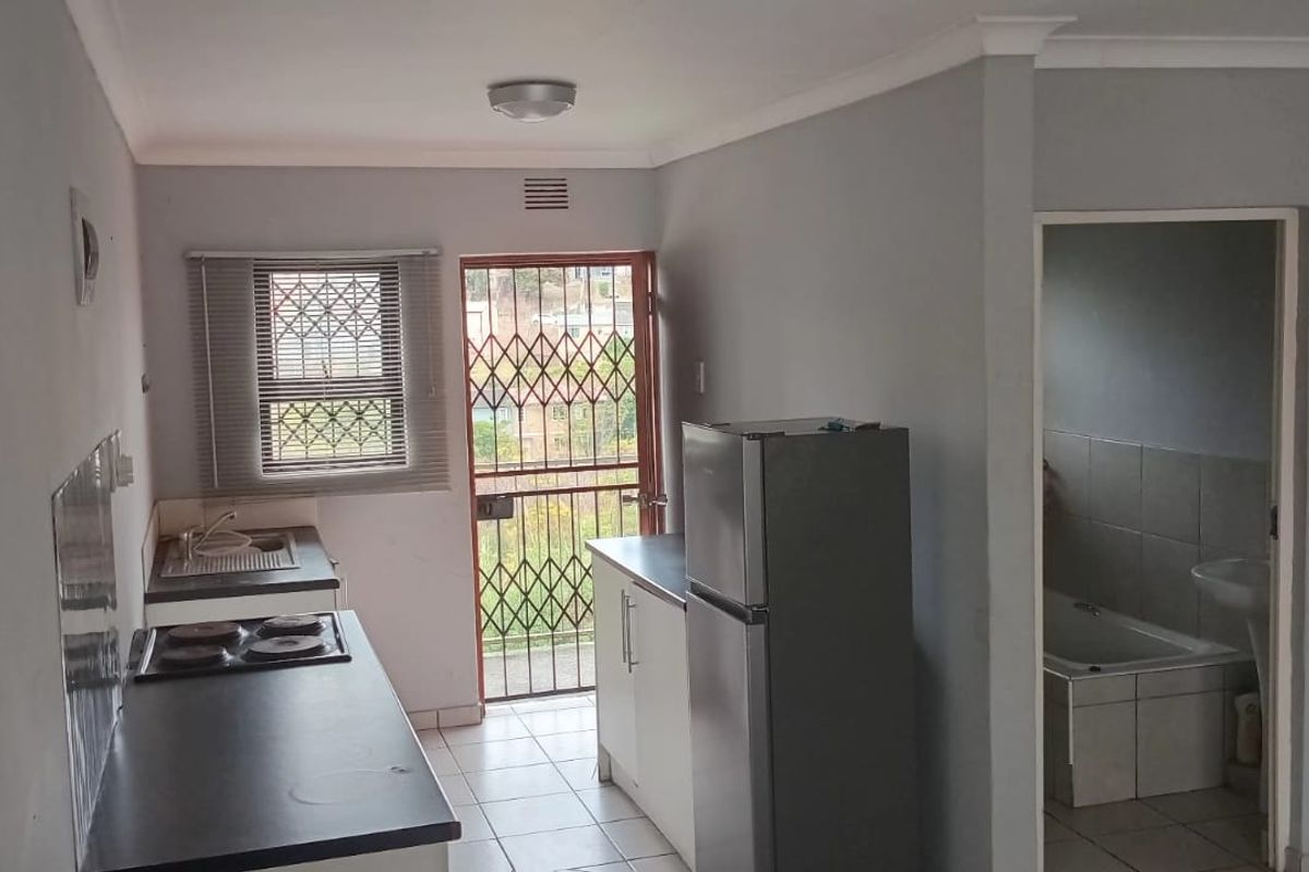 Compact kitchen featuring built-in cabinetry, a hob, and tiled flooring, with direct access to an exterior security gate.