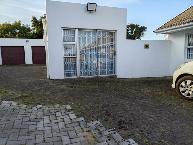 Front exterior view of the property featuring a paved driveway, security gate, and access to the garage and main entrance.