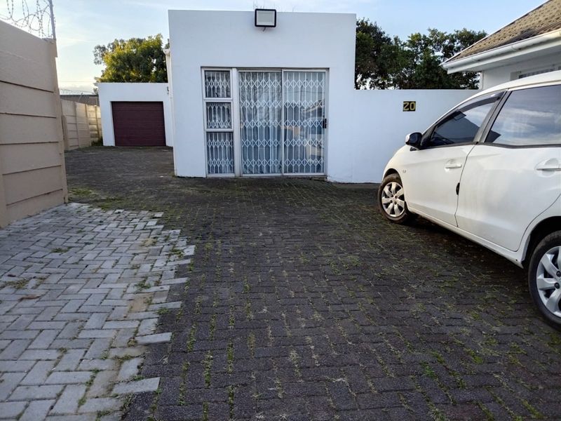 Front exterior view showing a paved driveway, security gate, and garage access.