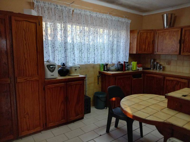 A dated kitchen featuring wooden cabinetry, tiled backsplash, and tiled flooring, offering a functional layout with potential for modern renovation.
