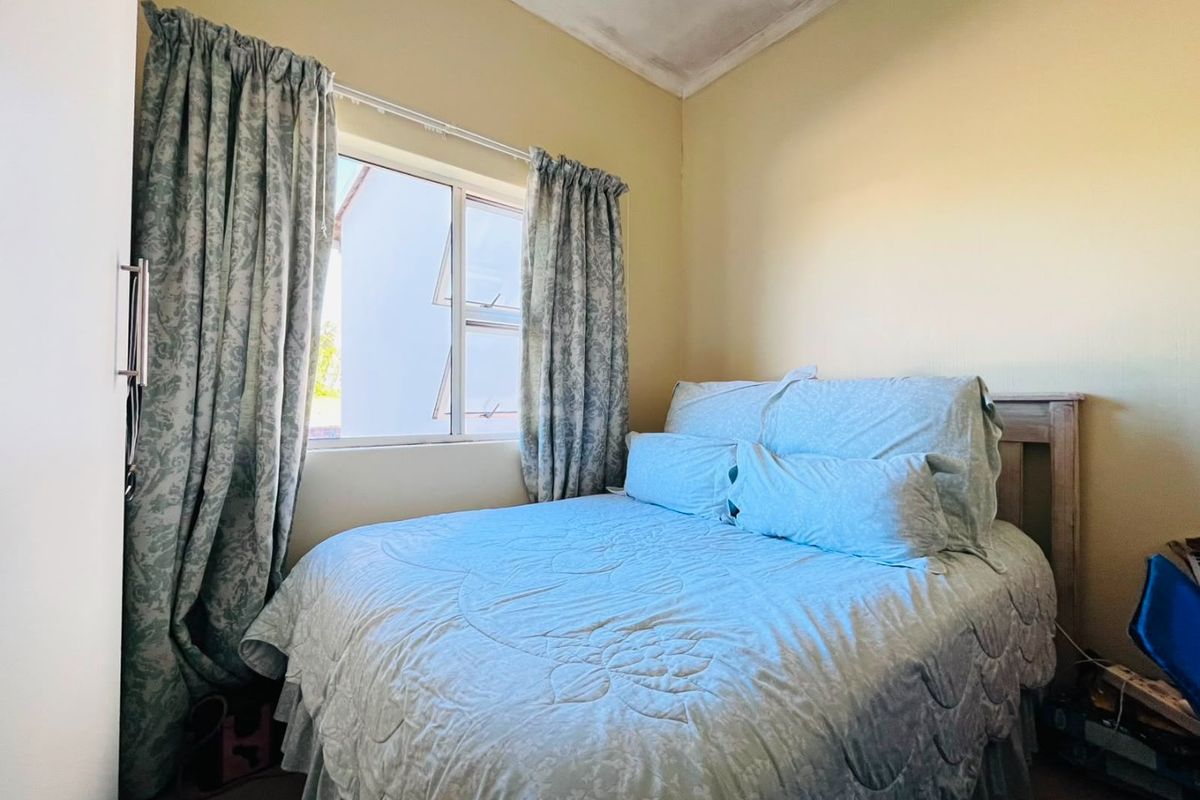 A compact bedroom featuring a sliding window and built-in storage, showing signs of ceiling water damage requiring maintenance.