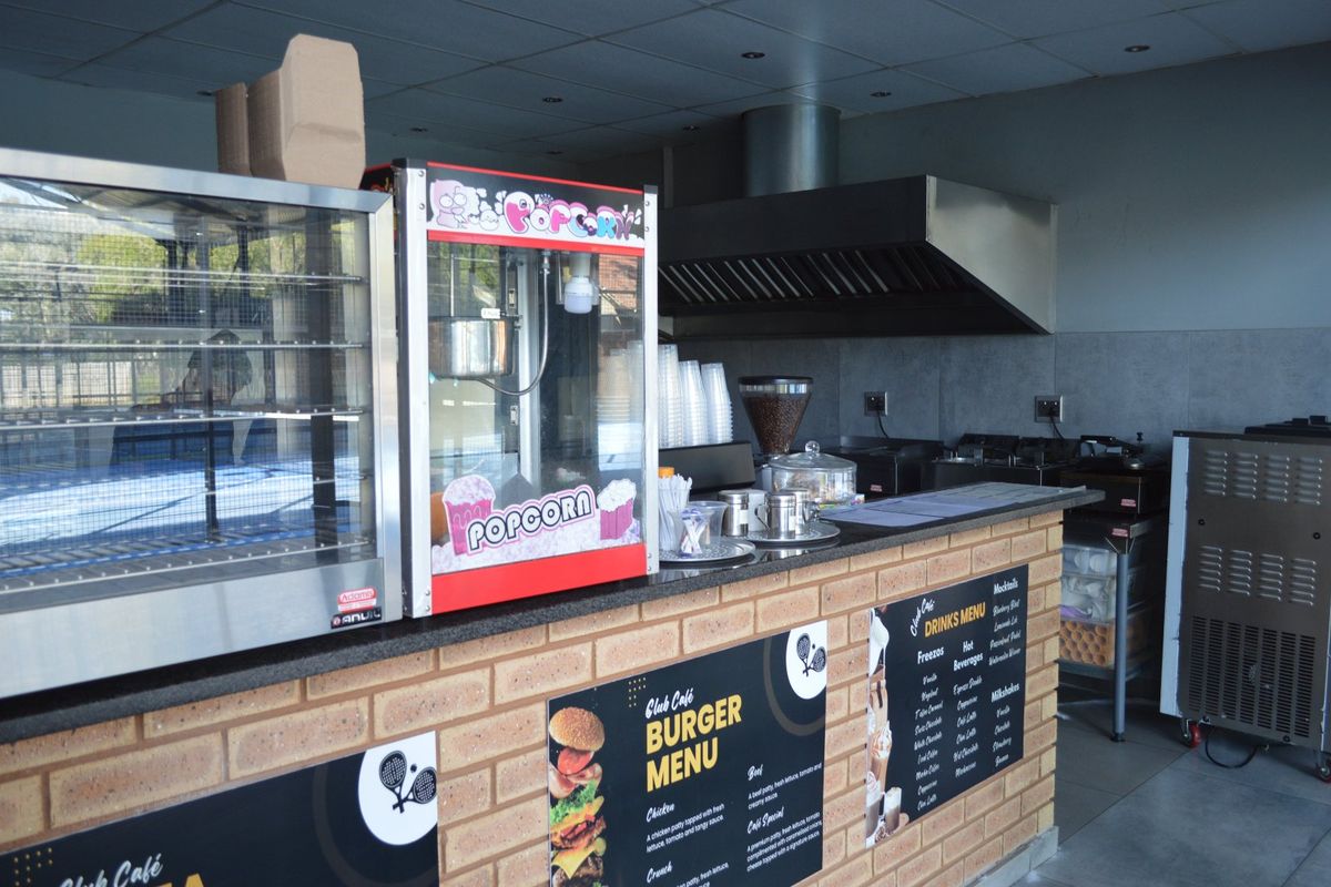 Commercial cafe service area featuring a brick-faced counter, granite work surfaces, and a professional stainless steel extractor hood.