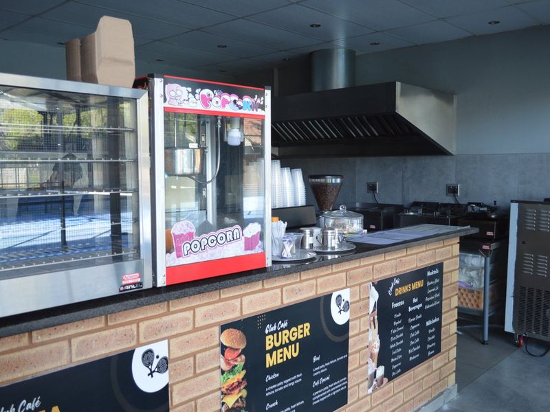 Commercial cafe service area featuring a brick-faced counter, granite work surfaces, and a professional stainless steel extractor hood.