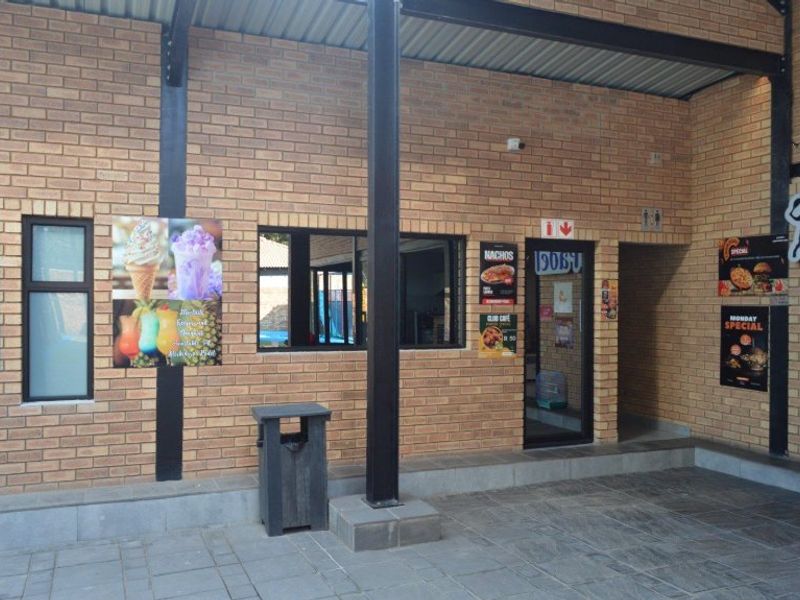 A commercial exterior patio area featuring face brick walls, steel structural columns, and paved flooring, providing access to the building interior.